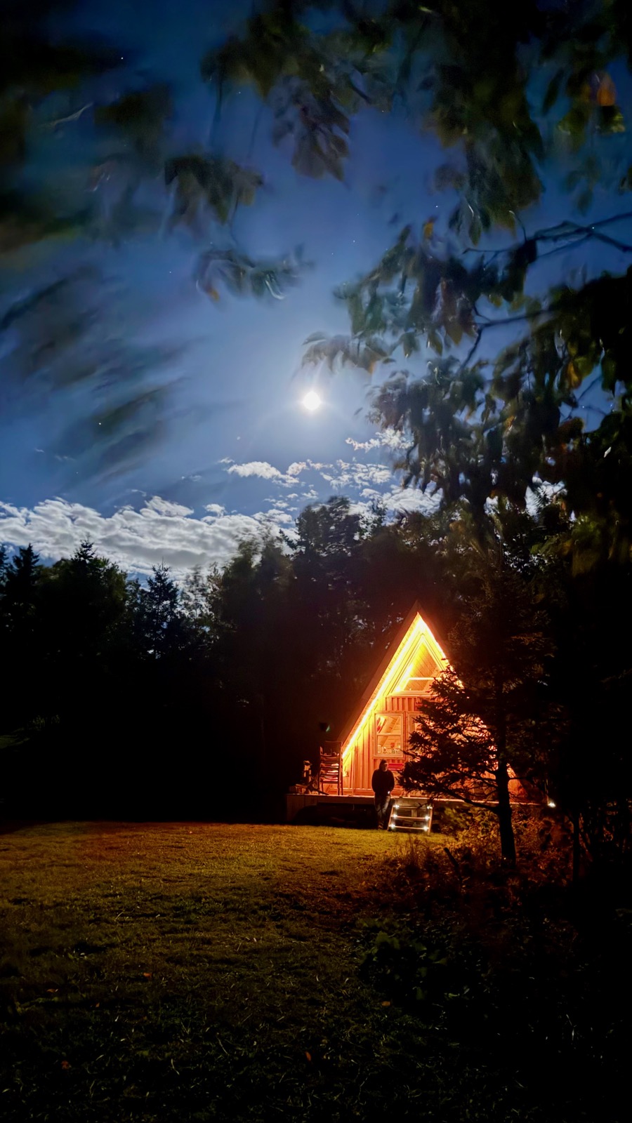 The lit aframe at night under a moonlit sky
